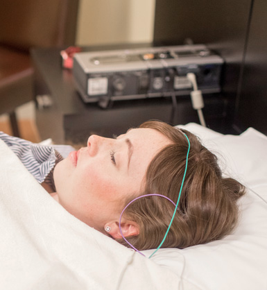 A patient laying in a bed, participating in a sleep study
