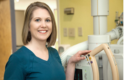 Smiling technician standing next to imaging equipment