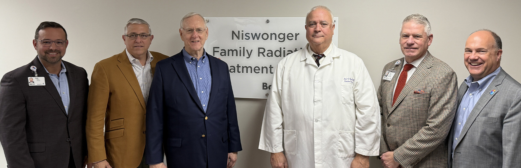 Group photo of Ballad Health and Niswonger executives in front of Niswonger Radiation Treatment sign