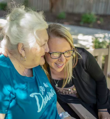 Young woman smiling and hugging an elderly woman