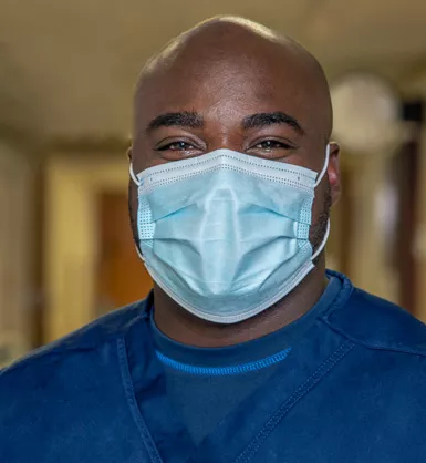 Man in blue scrubs wearing a surgical face mask
