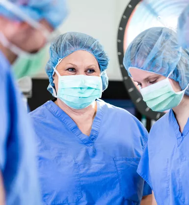 Sugical team in an operating room wearing masks, caps and scrubs