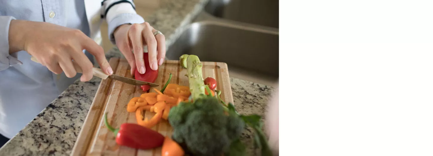 Close up photo of a person cutting up vegetables on a cutting board
