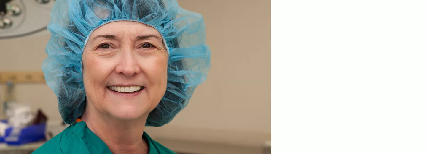 Doctor smiling in operating room wearing a disposable hair cover