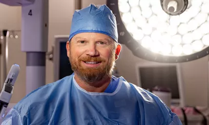 Surgeon wearing a surgical cap in operating room in front of a robotics surgery system