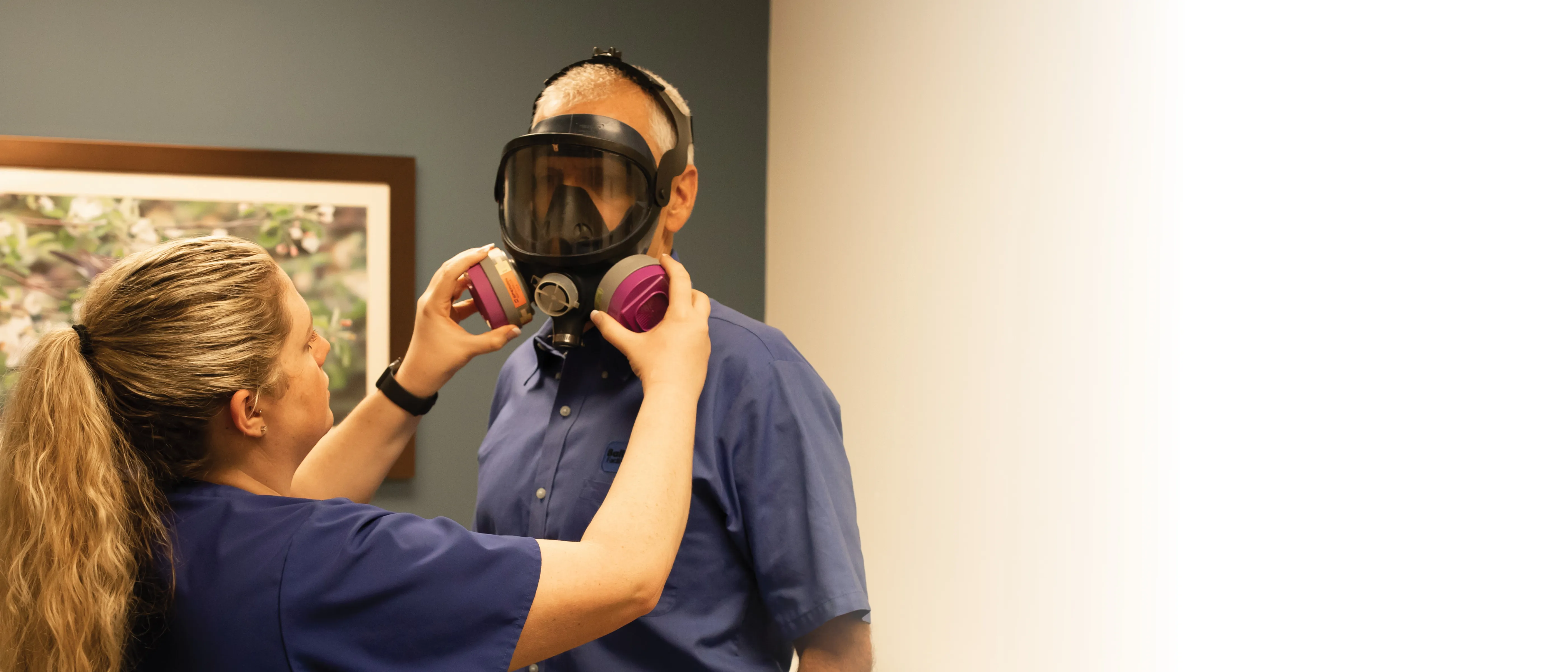 Occupational medicine staff attaching gas mask to client