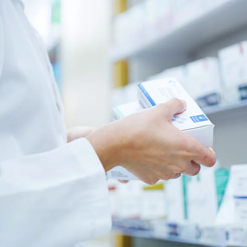 Photo of pharmacist holding two boxes of medication