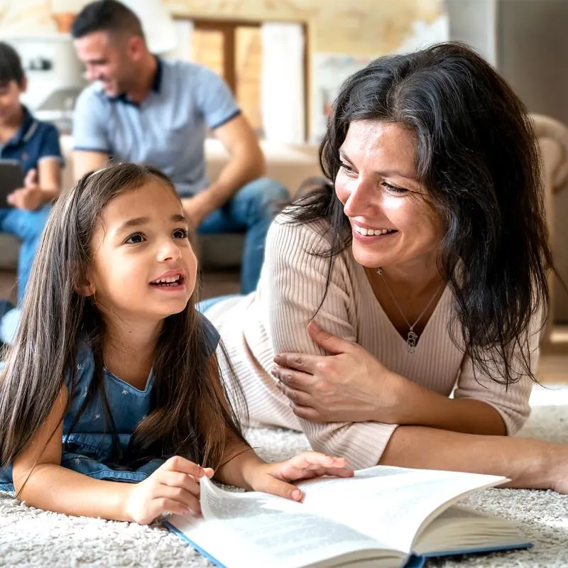 Mother and daughter laying down and reading a book together