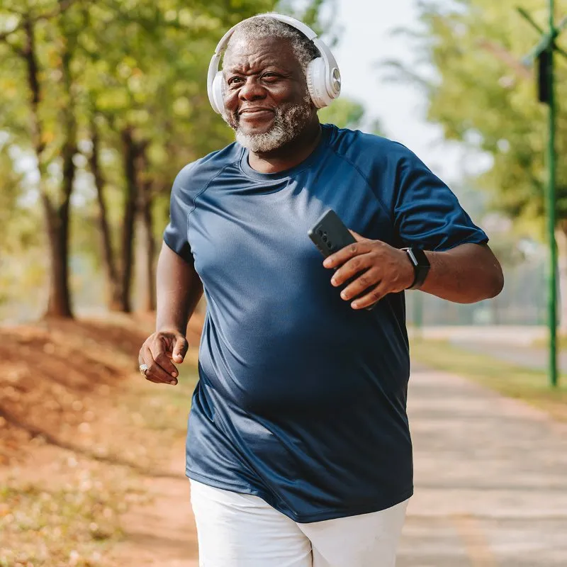 Man running on a shady path while listening to headphones