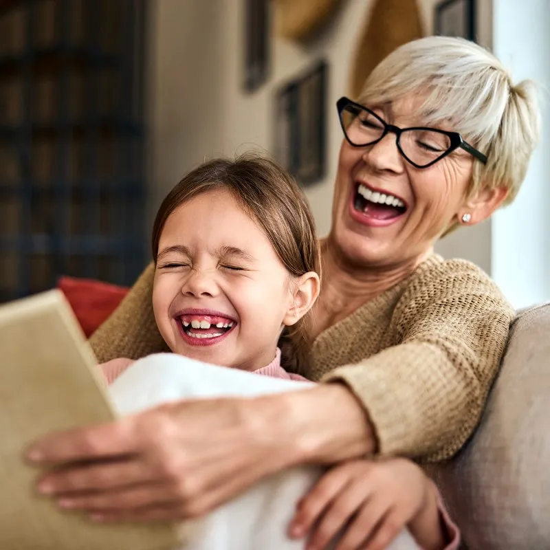 Older woman and child laughing while reading a book