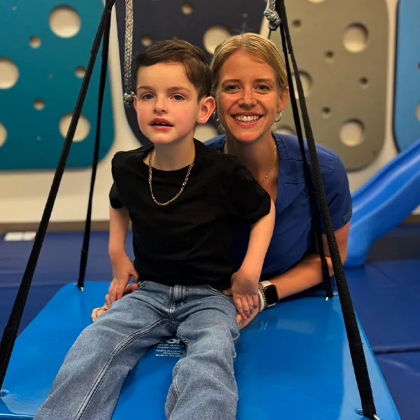Physical therapist pushing pediatric patient on a swing