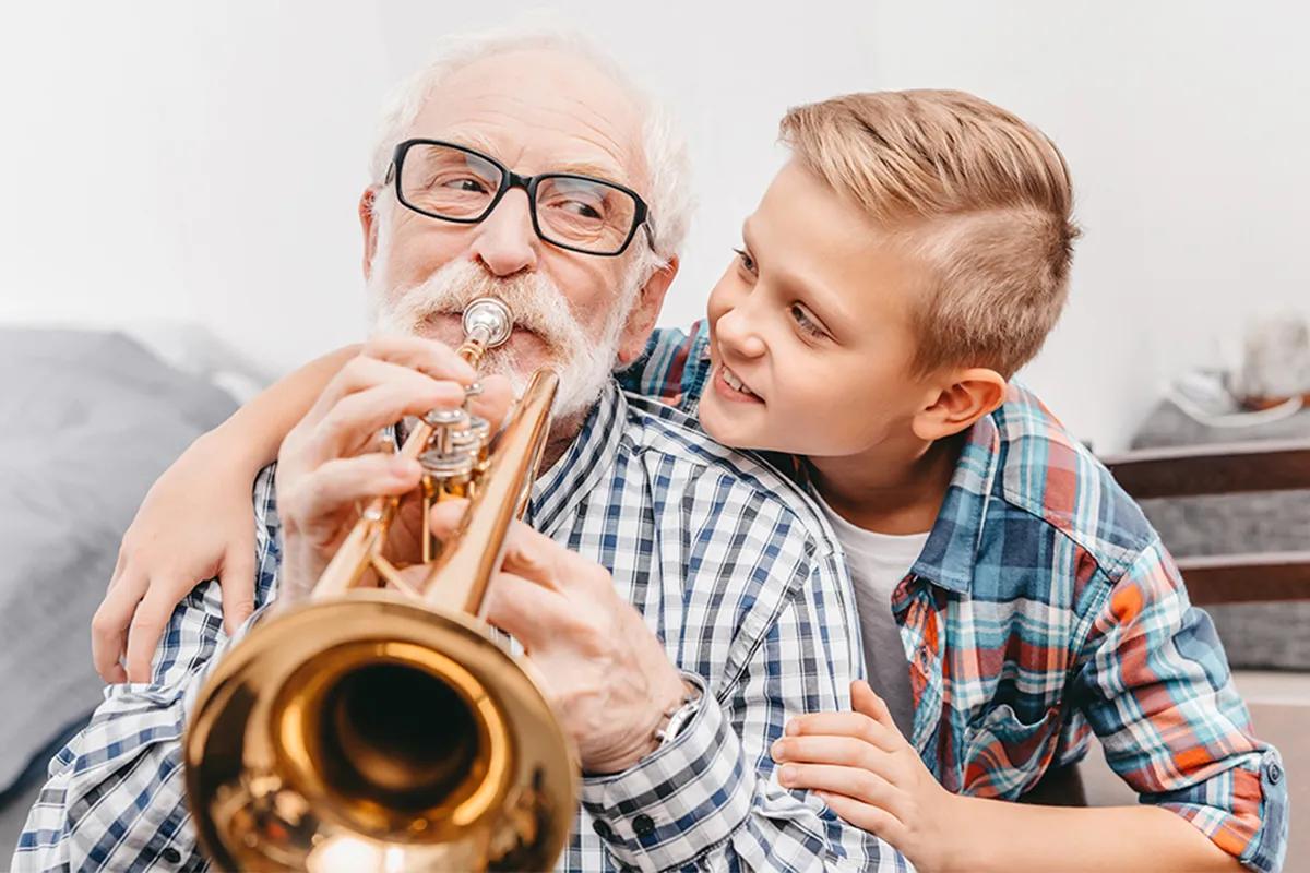 Elderly man with trumpet sitting next to his grandson